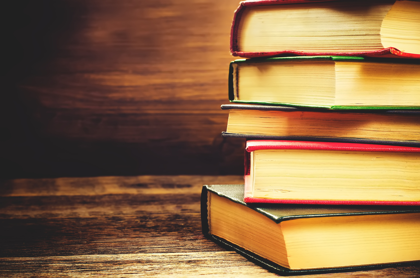 stack of books on the dark wood background. toning. selective focus on the middle book